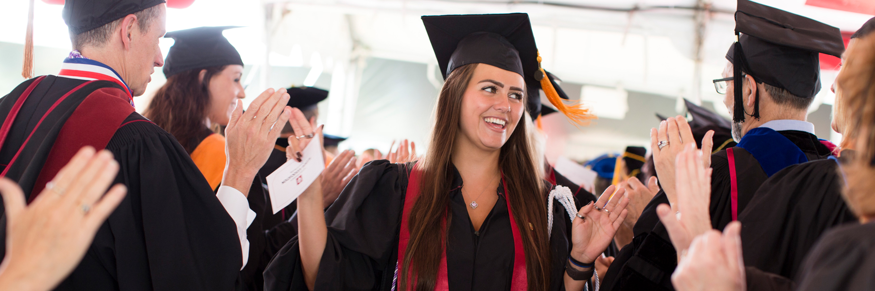 A student in a graduation cap gets high fives.